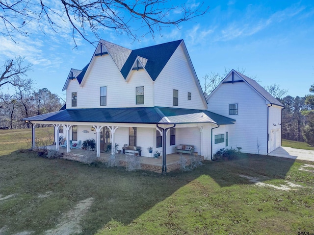 back of house featuring metal roof, covered porch, and a yard