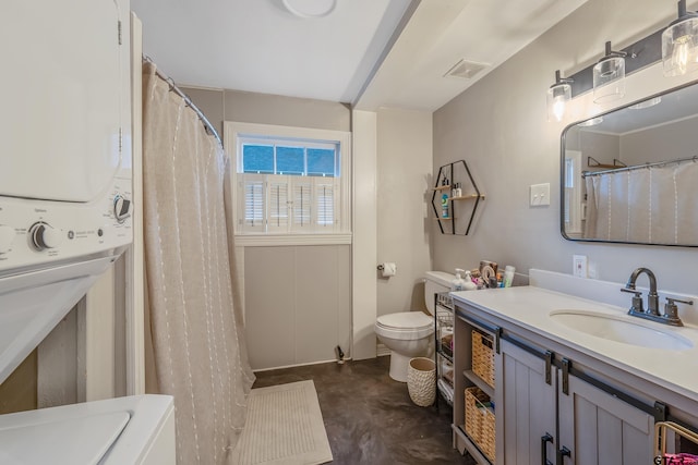 bathroom with vanity, stacked washer / drying machine, and toilet