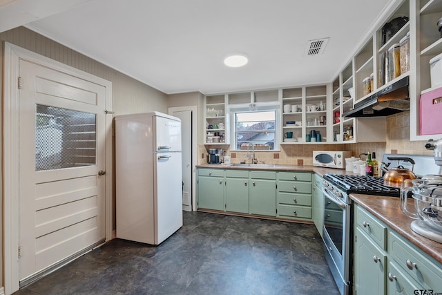 kitchen featuring white refrigerator, stainless steel range with gas cooktop, sink, and backsplash