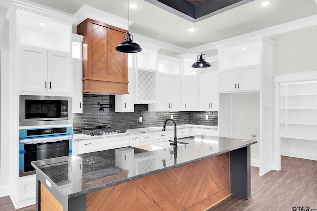 kitchen featuring sink, appliances with stainless steel finishes, an island with sink, white cabinets, and dark stone counters