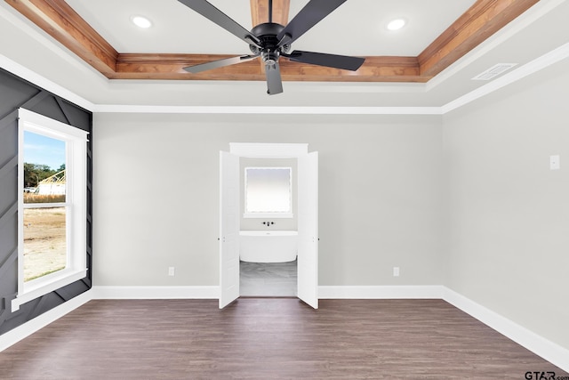 unfurnished bedroom featuring a tray ceiling, crown molding, dark hardwood / wood-style flooring, and ceiling fan