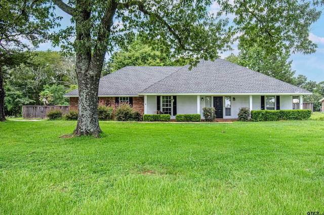 ranch-style house with covered porch, roof with shingles, and a front lawn
