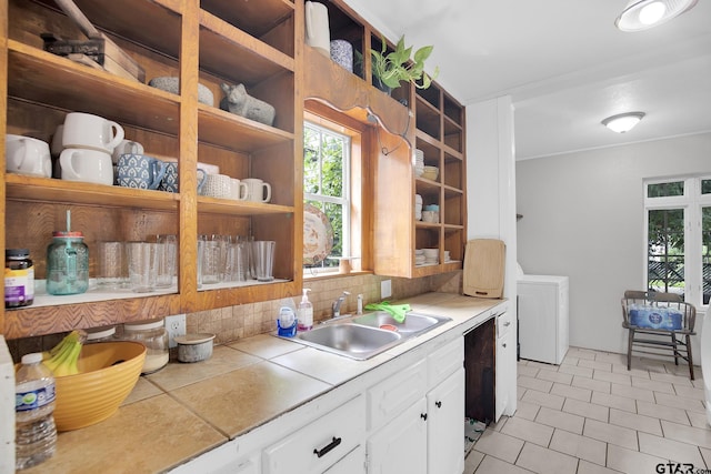 kitchen with tasteful backsplash, washer / dryer, sink, white cabinets, and dishwasher