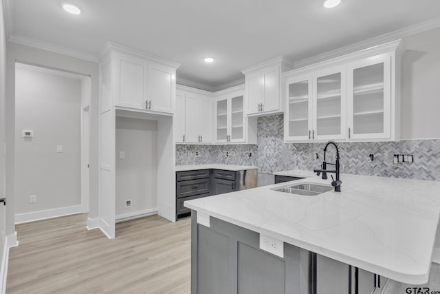 kitchen with white cabinets, crown molding, kitchen peninsula, and sink