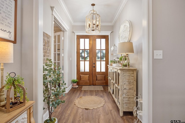 entryway with french doors, wood-type flooring, an inviting chandelier, and ornamental molding