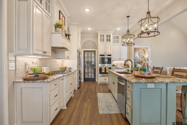 kitchen with appliances with stainless steel finishes, white cabinetry, a kitchen island with sink, and sink