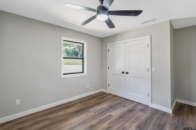 unfurnished bedroom with a closet, ceiling fan, and dark wood-type flooring