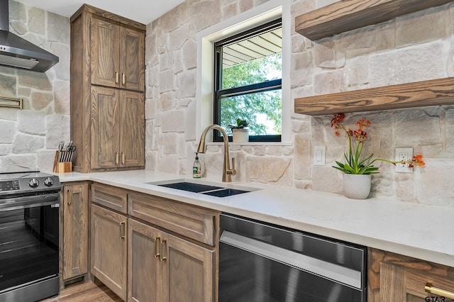 kitchen featuring black range oven, sink, stainless steel dishwasher, wall chimney exhaust hood, and light hardwood / wood-style floors