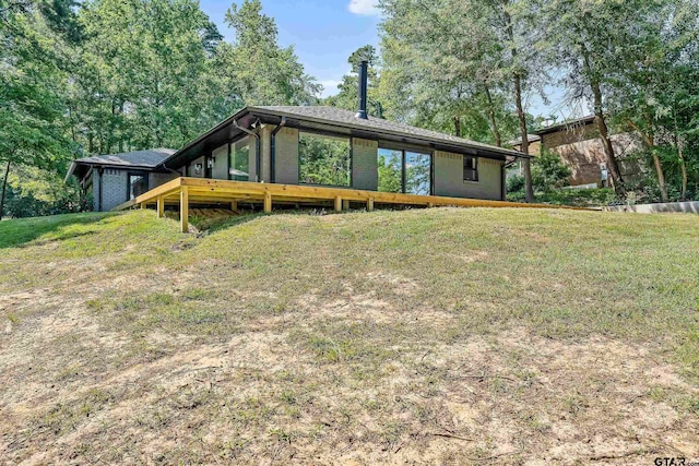 rear view of property featuring a lawn and a wooden deck