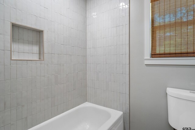 bathroom with toilet and tiled shower / bath