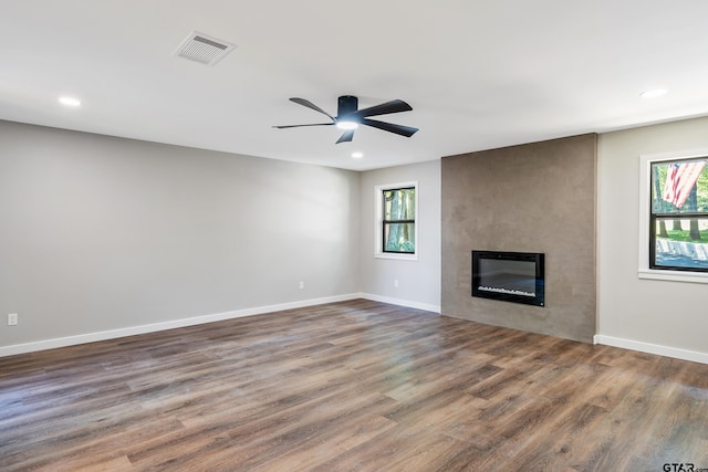 unfurnished living room with ceiling fan, a large fireplace, and dark hardwood / wood-style floors