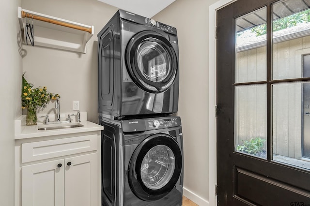 laundry room featuring cabinets, stacked washer and dryer, and sink