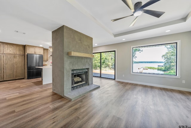 unfurnished living room featuring hardwood / wood-style flooring, plenty of natural light, and a tray ceiling