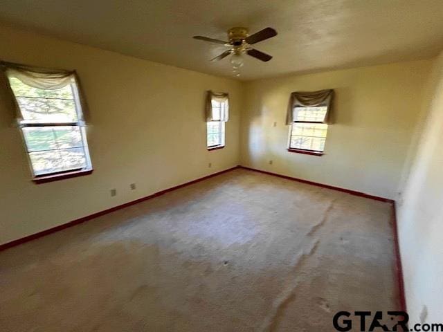 empty room with carpet flooring, ceiling fan, and plenty of natural light