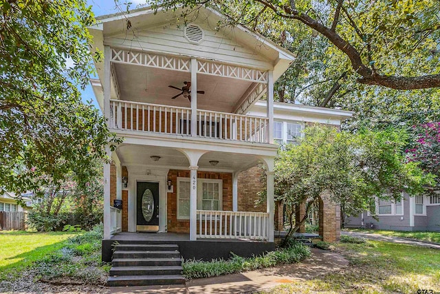 view of front of property featuring covered porch, a front lawn, ceiling fan, and a balcony