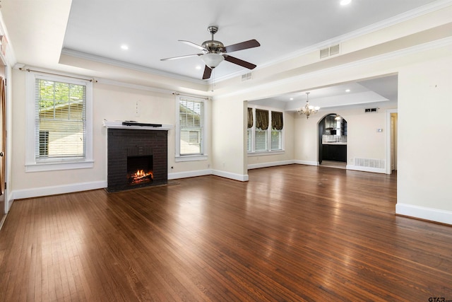 unfurnished living room with dark hardwood / wood-style flooring, a fireplace, a tray ceiling, and crown molding