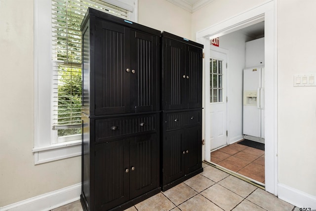 interior space with white fridge with ice dispenser, tile patterned flooring, and ornamental molding