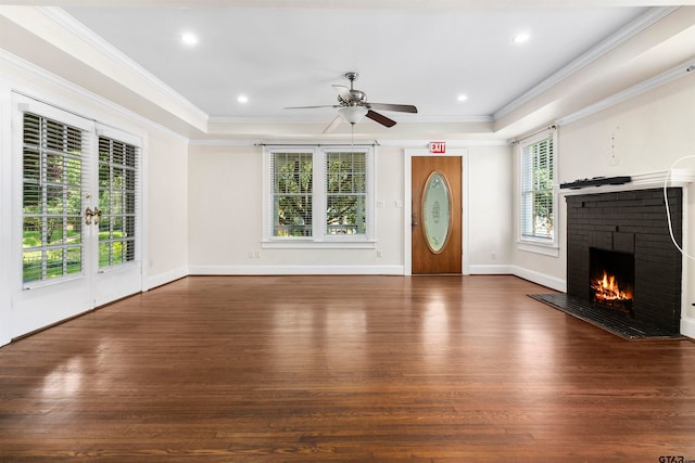 unfurnished living room with a brick fireplace, dark hardwood / wood-style flooring, ornamental molding, and ceiling fan