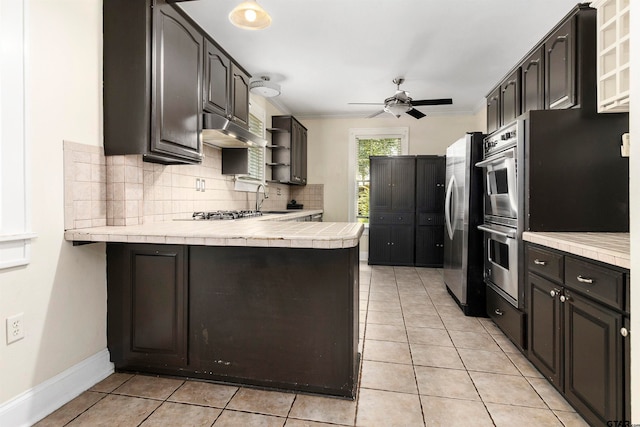 kitchen with kitchen peninsula, stainless steel appliances, light tile patterned flooring, and tasteful backsplash