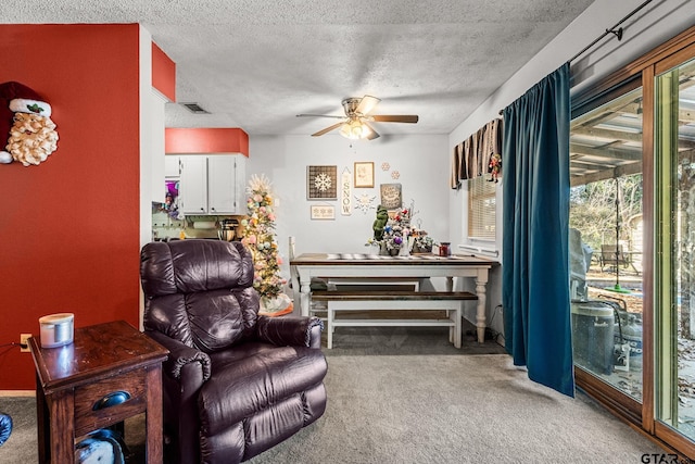 living area with carpet, ceiling fan, and a textured ceiling