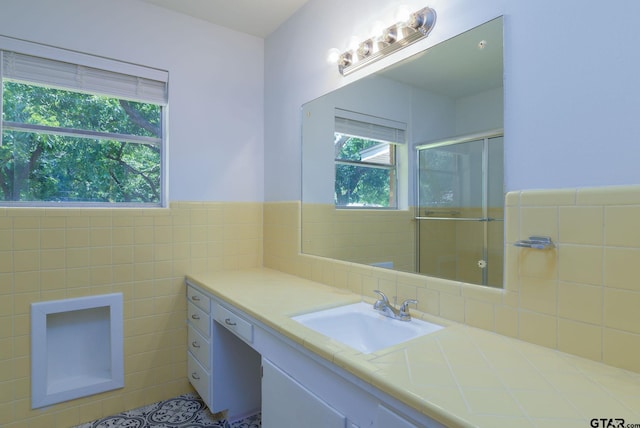 bathroom with tile patterned flooring, vanity, an enclosed shower, and tile walls