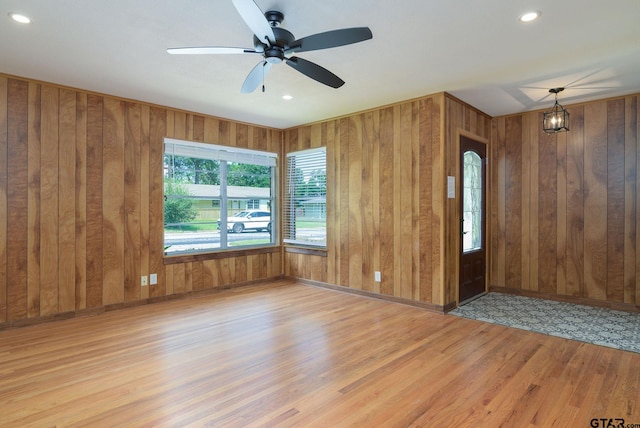 foyer entrance featuring wooden walls, ceiling fan, and light wood-type flooring