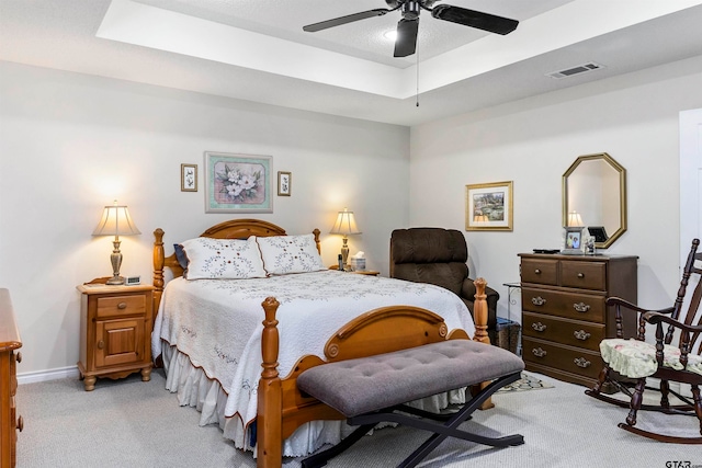 bedroom featuring light colored carpet, ceiling fan, and a raised ceiling