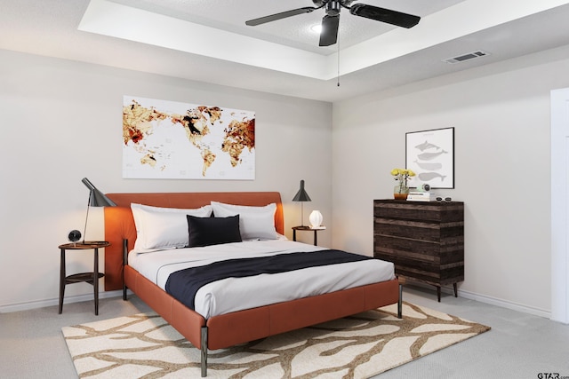 bedroom with light colored carpet, ceiling fan, and a tray ceiling