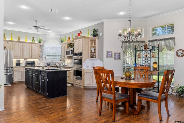 kitchen with stainless steel appliances, ornamental molding, ceiling fan with notable chandelier, a kitchen island, and dark wood-type flooring