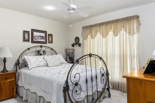 bedroom with a textured ceiling, light colored carpet, and ceiling fan