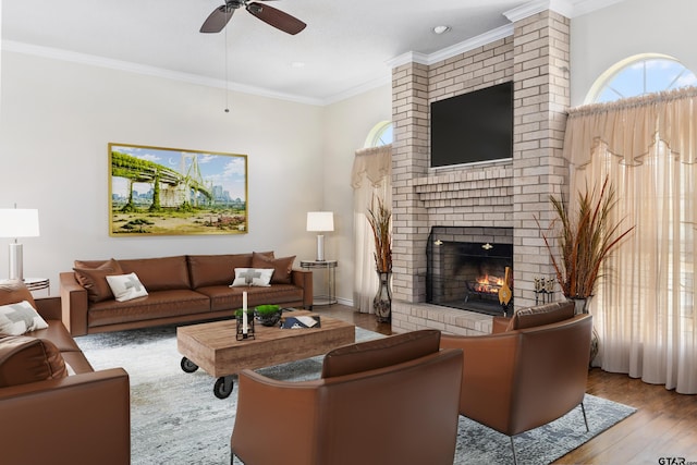 living room with ornamental molding, light wood-type flooring, ceiling fan, and a fireplace