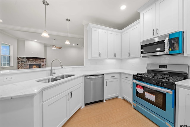 113 Hay Mdw, Winona, TX 75792 - kitchen with appliances with stainless steel finishes, a sink, ornamental molding, a ceiling fan, and a fireplace