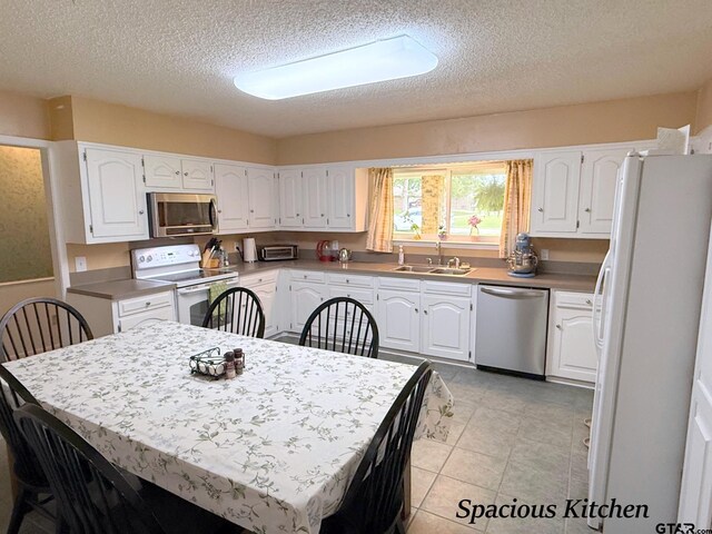 237 Oregon St, Van, TX 75790 - kitchen with stainless steel appliances, a textured ceiling, and white cabinets