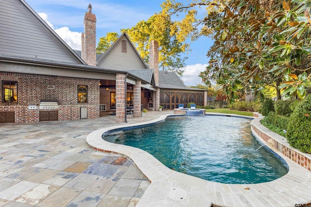 2205 Kingsmill Cir, Tyler, TX 75703 - view of swimming pool featuring exterior kitchen, a pool with connected hot tub, a patio, and grilling area