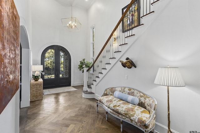 foyer entrance featuring baseboards, arched walkways, stairway, a high ceiling, and french doors