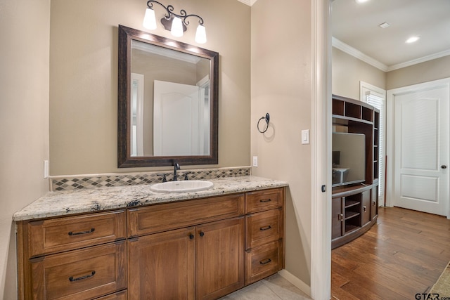 bathroom with crown molding, tasteful backsplash, vanity, wood finished floors, and baseboards