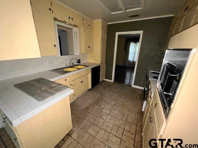 kitchen featuring sink, cream cabinets, range, crown molding, and dishwasher