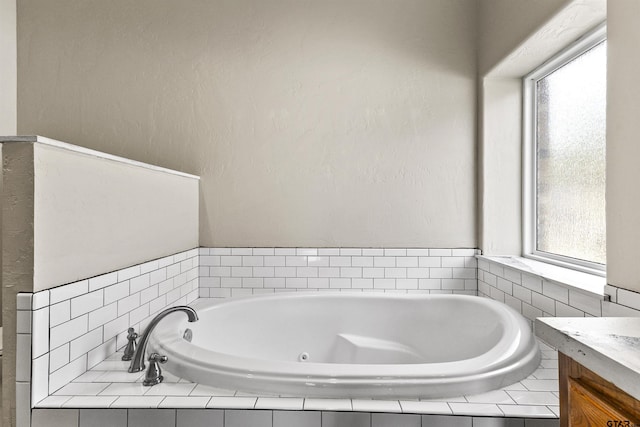 bathroom with vanity and tiled tub