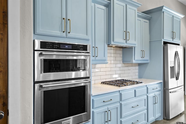 kitchen with blue cabinetry, appliances with stainless steel finishes, and decorative backsplash