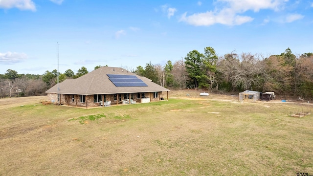 back of property with a lawn and solar panels