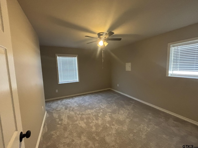 empty room with ceiling fan and dark colored carpet