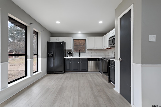 kitchen with white cabinets, a healthy amount of sunlight, appliances with stainless steel finishes, and light wood-type flooring