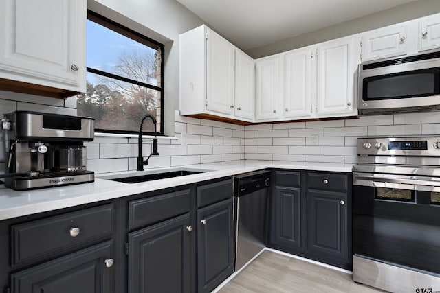 kitchen with sink, stainless steel appliances, white cabinetry, and tasteful backsplash