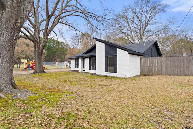 back of property featuring a playground and a yard