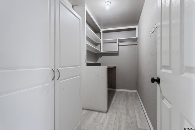 walk in closet with light hardwood / wood-style floors