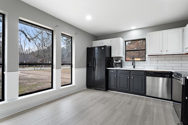 kitchen featuring sink, black fridge with ice dispenser, light wood-type flooring, dishwasher, and white cabinets