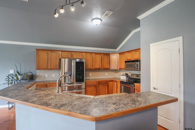 5734 Mustang Trl, Tyler, TX 75707 - kitchen with stainless steel appliances, vaulted ceiling, a sink, decorative backsplash, and brown cabinetry
