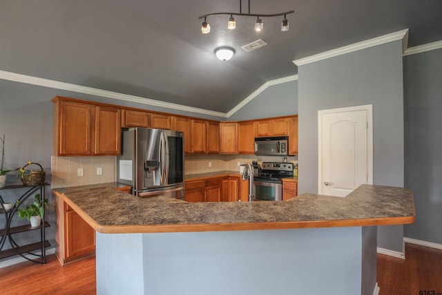 5734 Mustang Trl, Tyler, TX 75707 - kitchen featuring stainless steel appliances, wood finished floors, lofted ceiling, brown cabinets, and crown molding