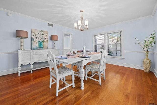 dining room featuring wood-type flooring, crown molding, and an inviting chandelier