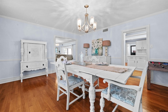 dining space featuring wood-type flooring, a notable chandelier, and ornamental molding